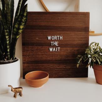 white Worth The Wait sign on brown wooden board by Hannah Busing courtesy of Unsplash.