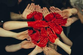 hands formed together with red heart paint by Tim Marshall courtesy of Unsplash.